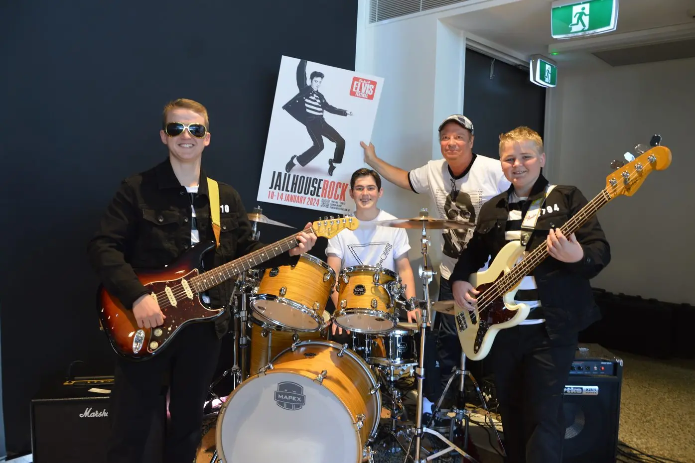 Brothers Kimball, Benson (drums) and McKay Sullivan from Cowra with Parkes Elvis Festival producer Julien Poulson and the 2024 festival program cover. Photo by Christine Little