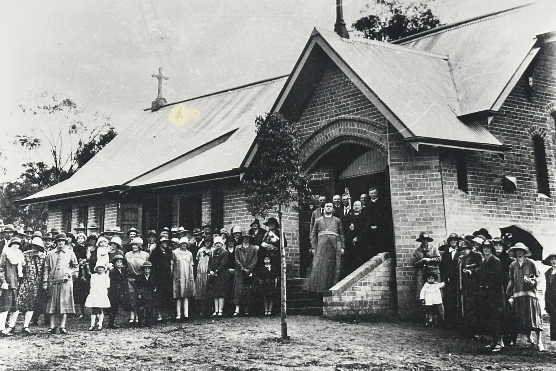 <p>Community members gather outside a local church for a group photograph, capturing a moment in the district\\u2019s early history.</p>\\n